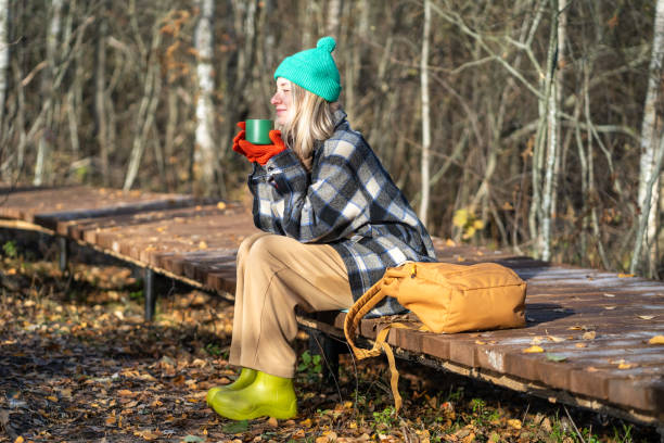 istock Time alone. Relaxed middle aged woman enjoy calm weekend in fall park meditative drinks thermos tea. 2170864211