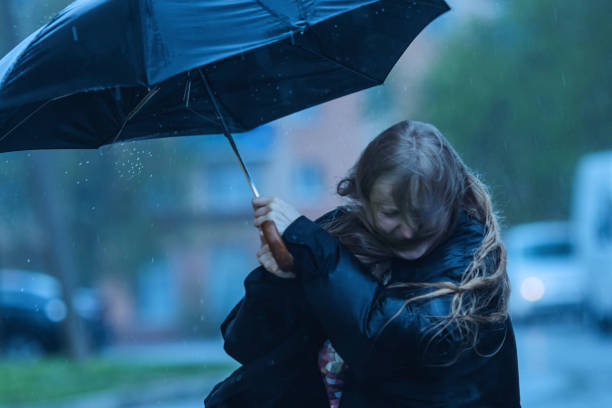 back view of a couple embracing on bench under a shared umbrella while enjoying the rain, highlighting love and connection amidst a tranquil natural backdrop of greenery.