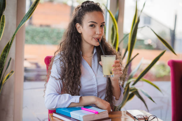 Female student taking a break from studying and having a sip of the refreshing lemonade