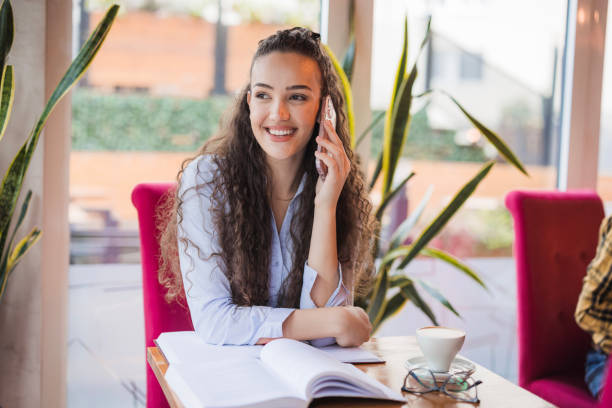 Joyful student looking through the cafeteria window when taking via mobile phone