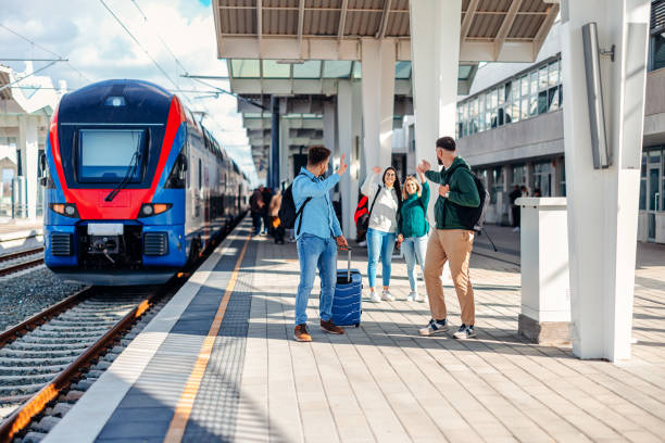 Two friends wave goodbye to another pair at the train station, their gestures a silent promise of memories cherished and future reunions