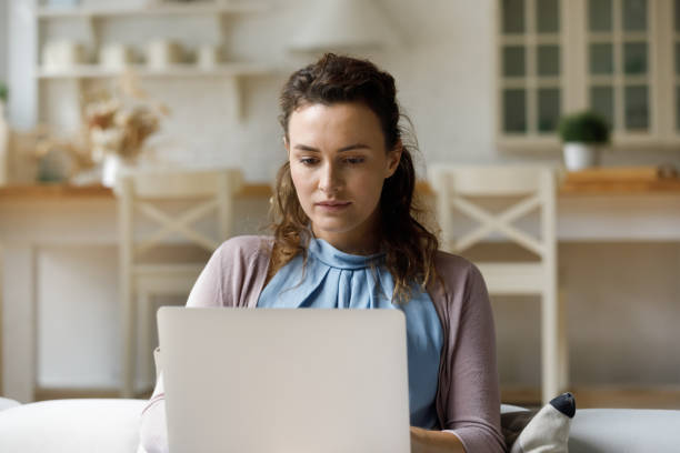 istock Serious millennial woman using laptop, sitting on home couch 2170875161
