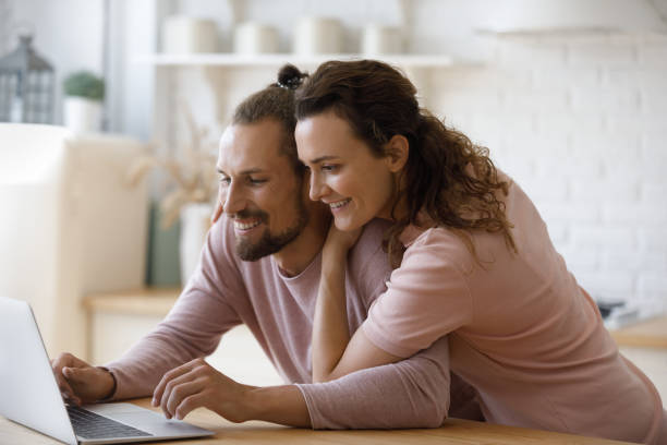istock Happy couple using online service on laptop in home kitchen 2170875755