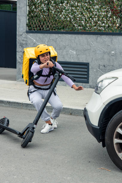 istock Latin courier with yellow backpack and helmet falling from electric scooter after being hit by car 2170876623