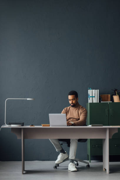 istock Man Working at a Modern Desk with Laptop and Lamp 2170879147