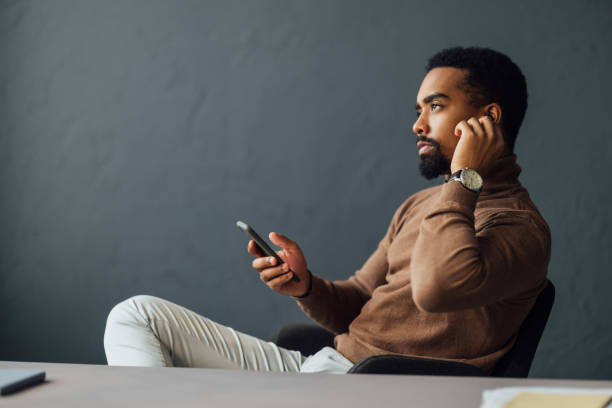 istock Thoughtful Man Relaxing in Office Holding Smartphone 2170879162