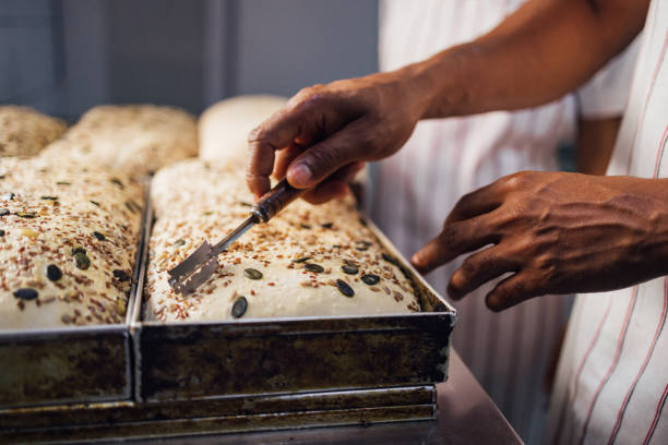 Baker Preparing Seed-Topped Bread Dough for Baking