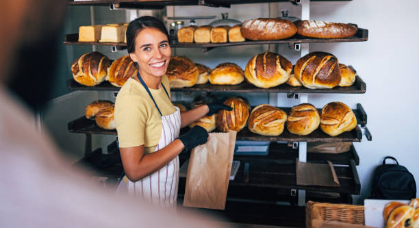 Friendly Baker Smiling While Serving Fresh Bread in Bakery