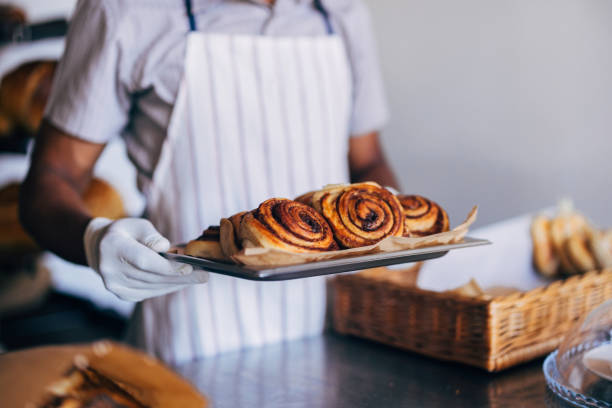istock Baker Holding Freshly Baked Cinnamon Rolls On Tray 2170880624