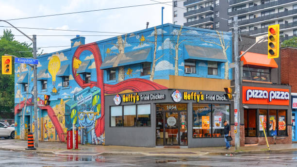 Toronto, Canada - September 10, 2024: A man walks by a small business at a city corner. Heffy's Fried Chicken is the name and it has decorated exterior walls.