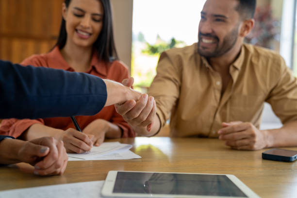 istock Couple buying a house and signing the deed while handshaking 2170888049