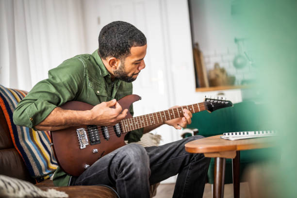 istock Black Male Showcases Guitar Skills in Home Setting 2170888484