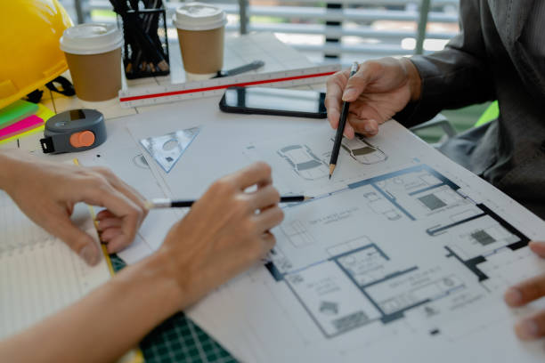 istock engineers are sitting discussing a construction plan that needs to be revised to make the structure stronger, an architect and assistant are brainstorming and examining the blueprints 2170894933