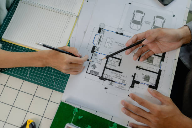 istock engineers are sitting discussing a construction plan that needs to be revised to make the structure stronger, an architect and assistant are brainstorming and examining the blueprints 2170894939
