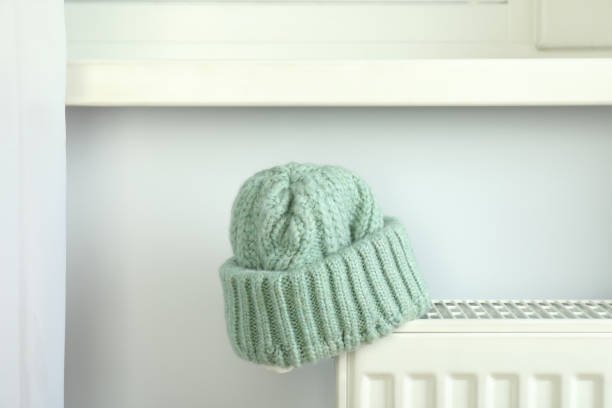 Concept of heating season with knitted hat on radiator.