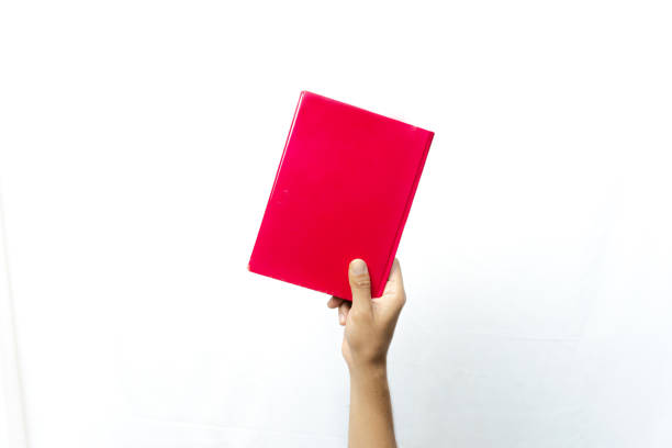 istock A hand holds a bright red book, against a plain white background. The book has a simple cover with a single uniform color. 2170905704