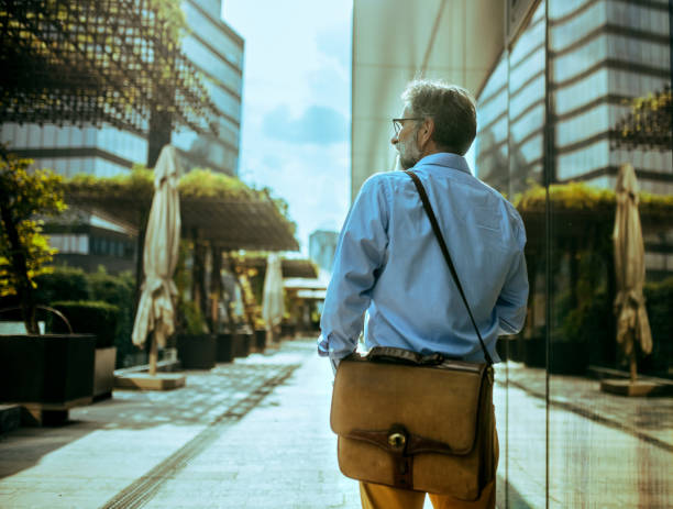 istock Handsome senior businessman standing at street and using smart phone for communication. Modern buildings in background. 2170906533