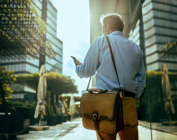 istock Handsome senior businessman standing at street and using smart phone for communication. Modern buildings in background. 2170906589