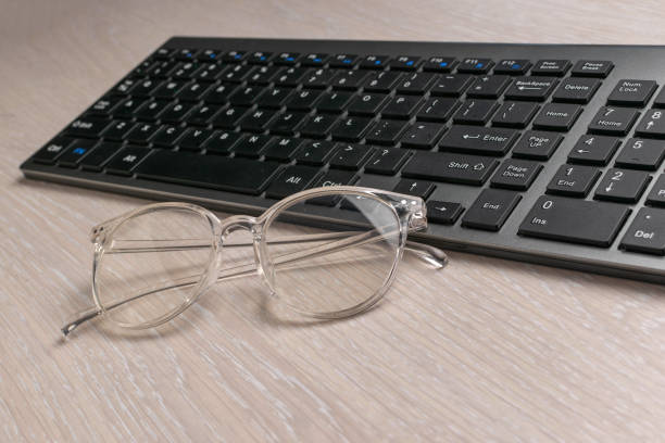 istock Clear Glasses and Black Wireless Keyboard on Light Wooden Desk 2170909908
