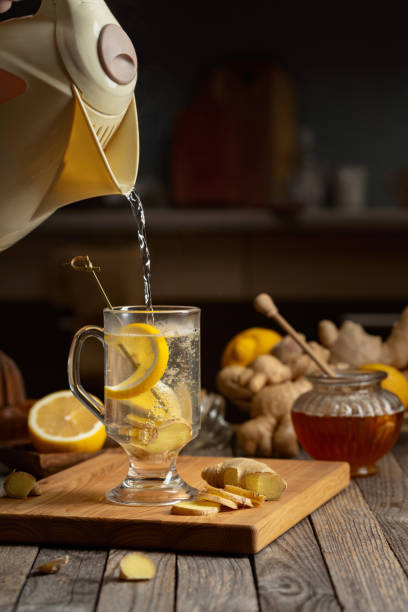 Hot water is poured into a glass for preparing ginger tea.