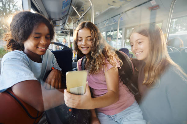 istock Happy students using cell phone while traveling to school in a bus. 2170919275