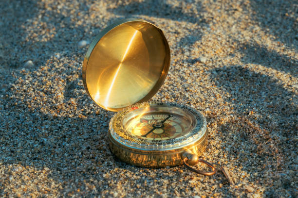Compass in the sand, vintage navigational equipment on the beach, selective focus