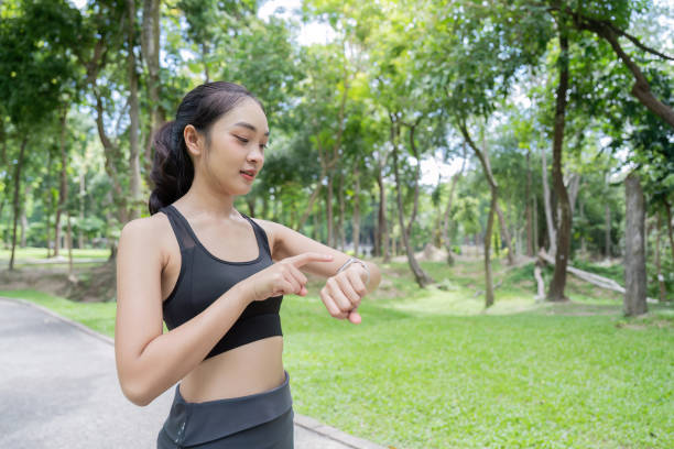 istock Asian woman checking smartwatch while enjoying tranquil park setting 2170921668