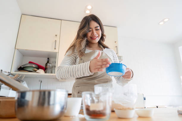 istock Smiling Asian woman adding ingredients while baking in kitchen 2170922223