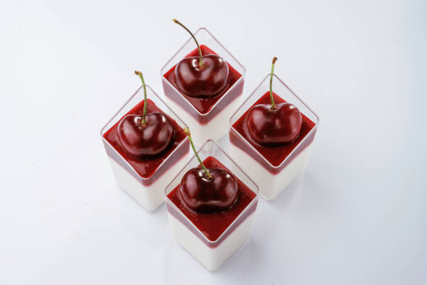 Panna cotta with cherry against white background.