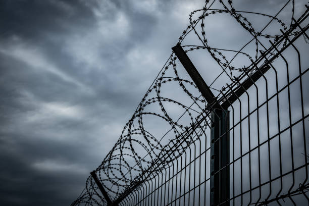 istock Barbed wire fence with dark clouds sky 2170927317