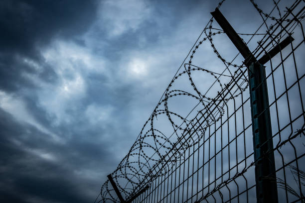 istock Barbed wire fence with dark clouds sky 2170927924