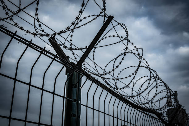 istock Barbed wire fence with dark clouds sky 2170927955