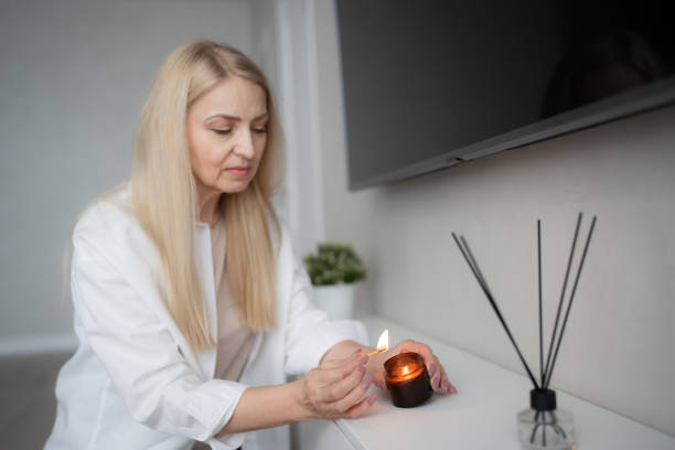 istock A woman is lighting a candle in her cozy home, near a reed diffuser, creating a calm atmosphere 2170928032