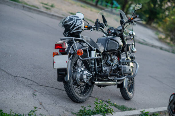An old motorcycle is parked by the road.