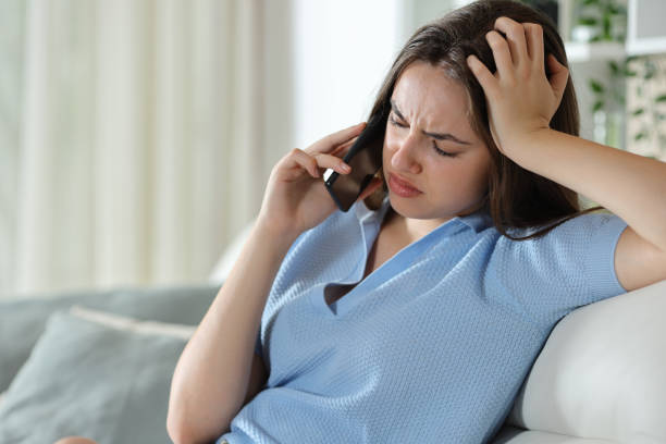 istock Sad woman talking on phone sitting on a sofa 2170930119