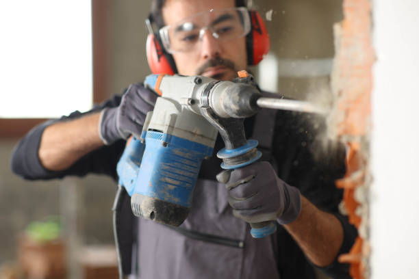 Construction worker wrecking wall using rotary hammer stock photo