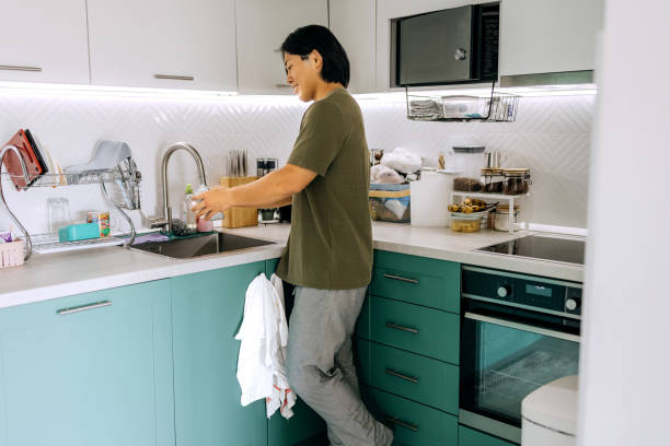 istock Young smiling casually clothed man washing dishes at home 2170930853