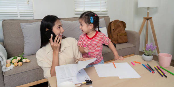 istock Mom multitasking with phone and papers at home with daughter 2170931081