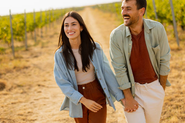 istock Couple strolls hand in hand along a sunlit path amidst lush vineyards during a warm afternoon 2170931391