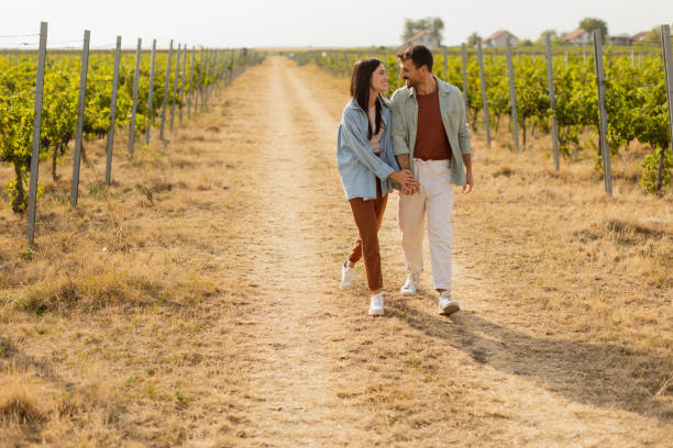 istock Couple strolls hand in hand along a sunlit path amidst lush vineyards during a warm afternoon 2170931397