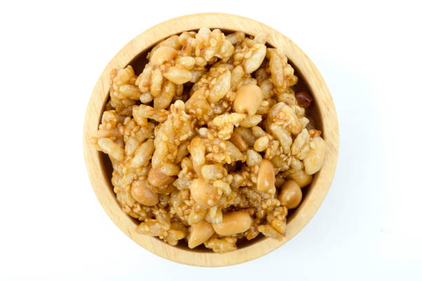 A wooden cup of Kra-ya-sat, Thai dessert, prepared for Buddhist religious events, isolated on white background top view flat lay clipping path, stack. kra-ya-sat, postre tailandés preparado para eventos religiosos budistas, fiesta tailandesa, hecho de maní, caña de azúcar, arroz pegajoso, sésamo y coco, similar en apariencia a una barra de granola, pero con un sabor más dulce y muy pegajoso.