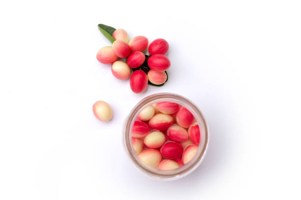 Top view of fresh Bengal-currant or Carandas-plum or Karanda fruits with green leaves and pickled in glass bottle isolated on white background  Top view. Flat lay.