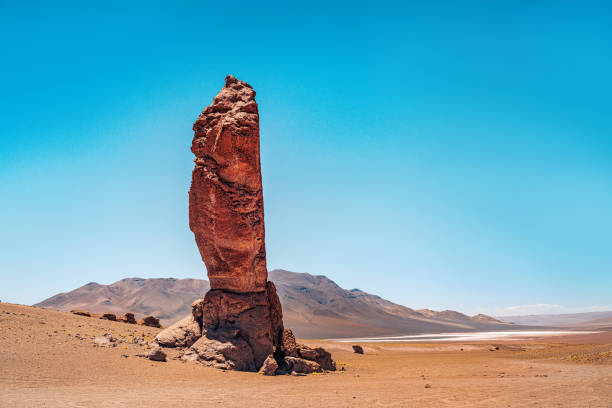 Captivating view of a unique rock formation in the vast Atacama Desert, Chile, highlighting the arid landscape against a clear blue sky.