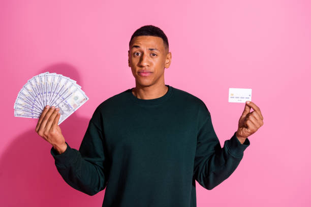 istock Photo of funky doubtful guy dressed pullover holding dollars fan bank card emtpy space isolated pink color background 2170934546