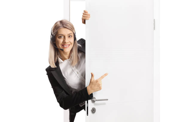 istock Female call operator with a headset standing behind a door and pointing 2170938424