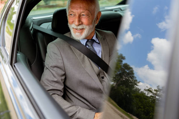 istock Senior gentleman in a sharp suit smiling while buckled up in his car 2170940142
