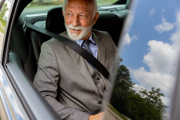 istock Senior gentleman in a sharp suit smiling while buckled up in his car 2170940166