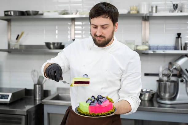 istock Male pastry chef holds a cut mousse cake in his hands. 2170940308