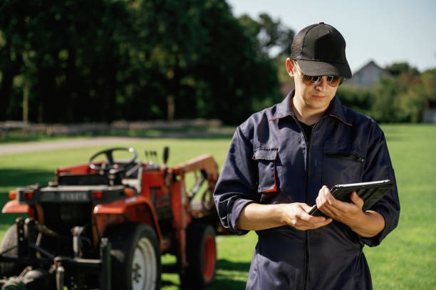 istock Black digital tablet in hands. Man is with utility tractor with grass cutter and aerator equipment on the field 2170941405