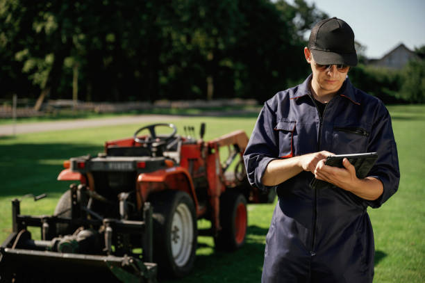 istock Black digital tablet in hands. Man is with utility tractor with grass cutter and aerator equipment on the field 2170941406